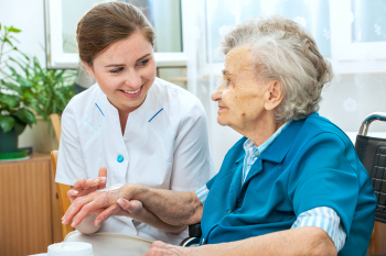 caregiver putting some cream in the hand of senior woman